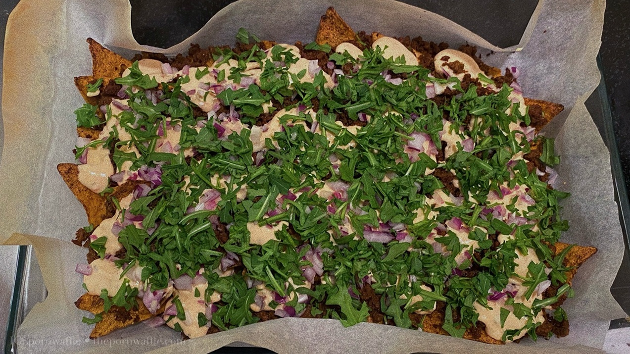 Nachos with minced meat, red onion, parmesan, chopped arugula and ranch dip.